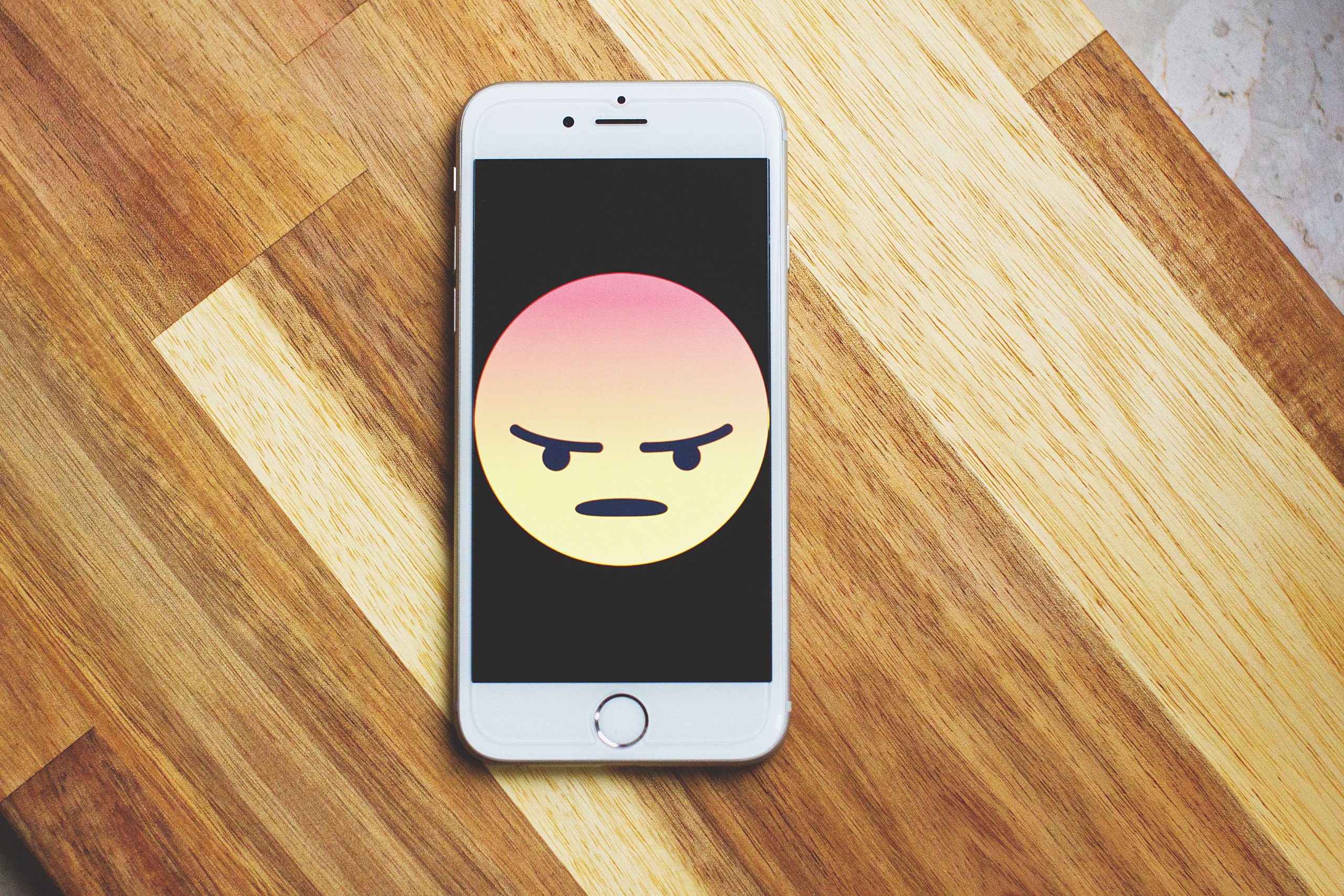 Téléphone affichant un emoji frustré sur table