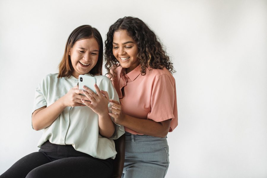 Deux femmes souriantes regardant smartphone ensemble