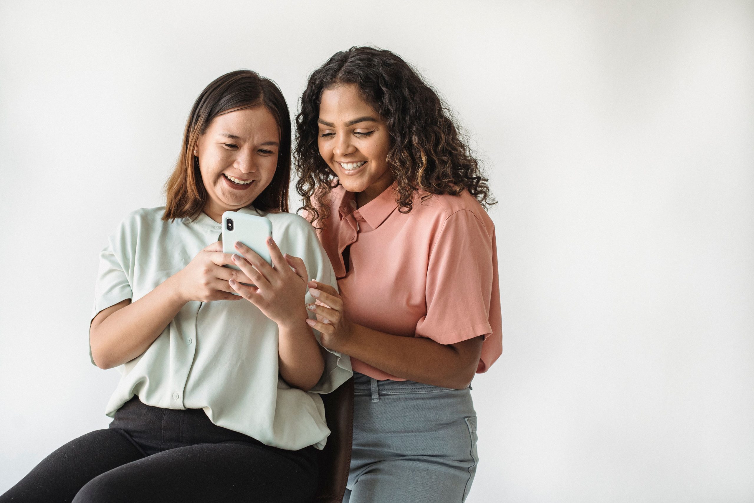 Deux femmes souriantes regardant smartphone ensemble