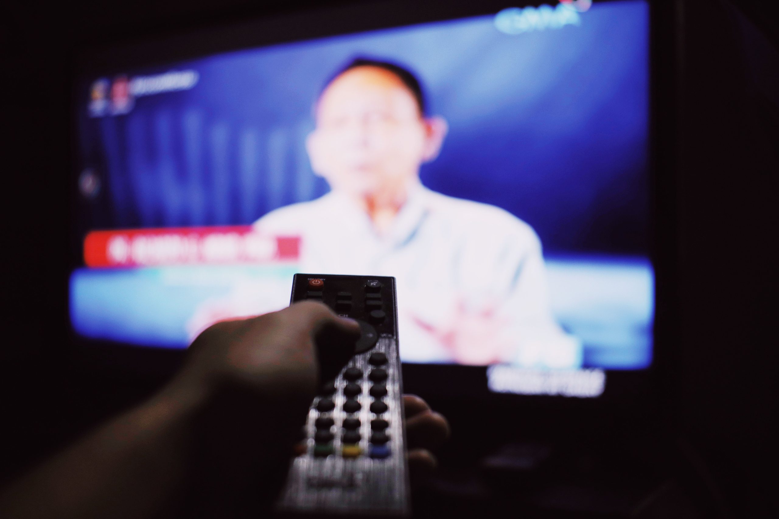 Personne changeant de chaîne TV avec télécommande