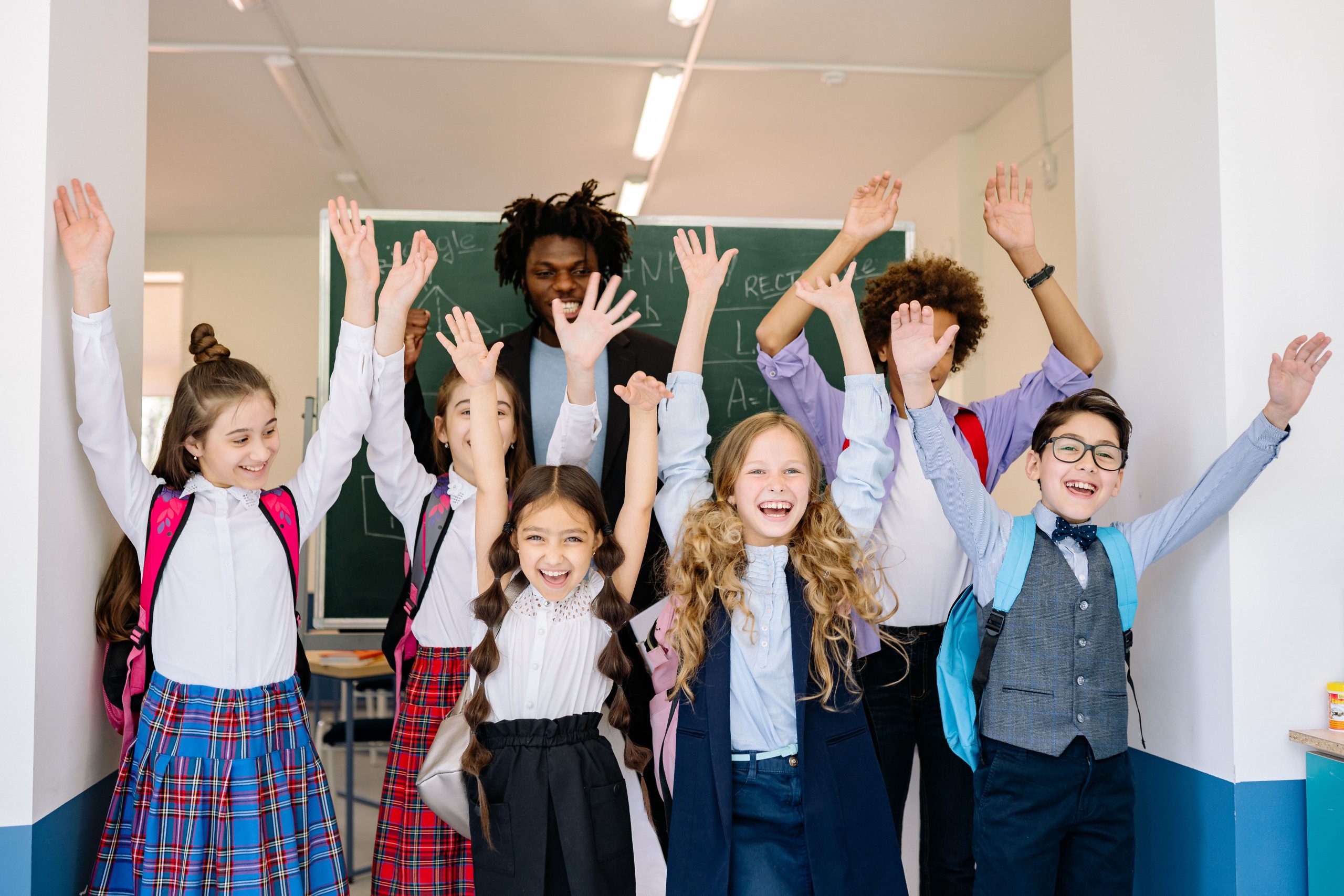 Enfants diversifiés levant la main en classe