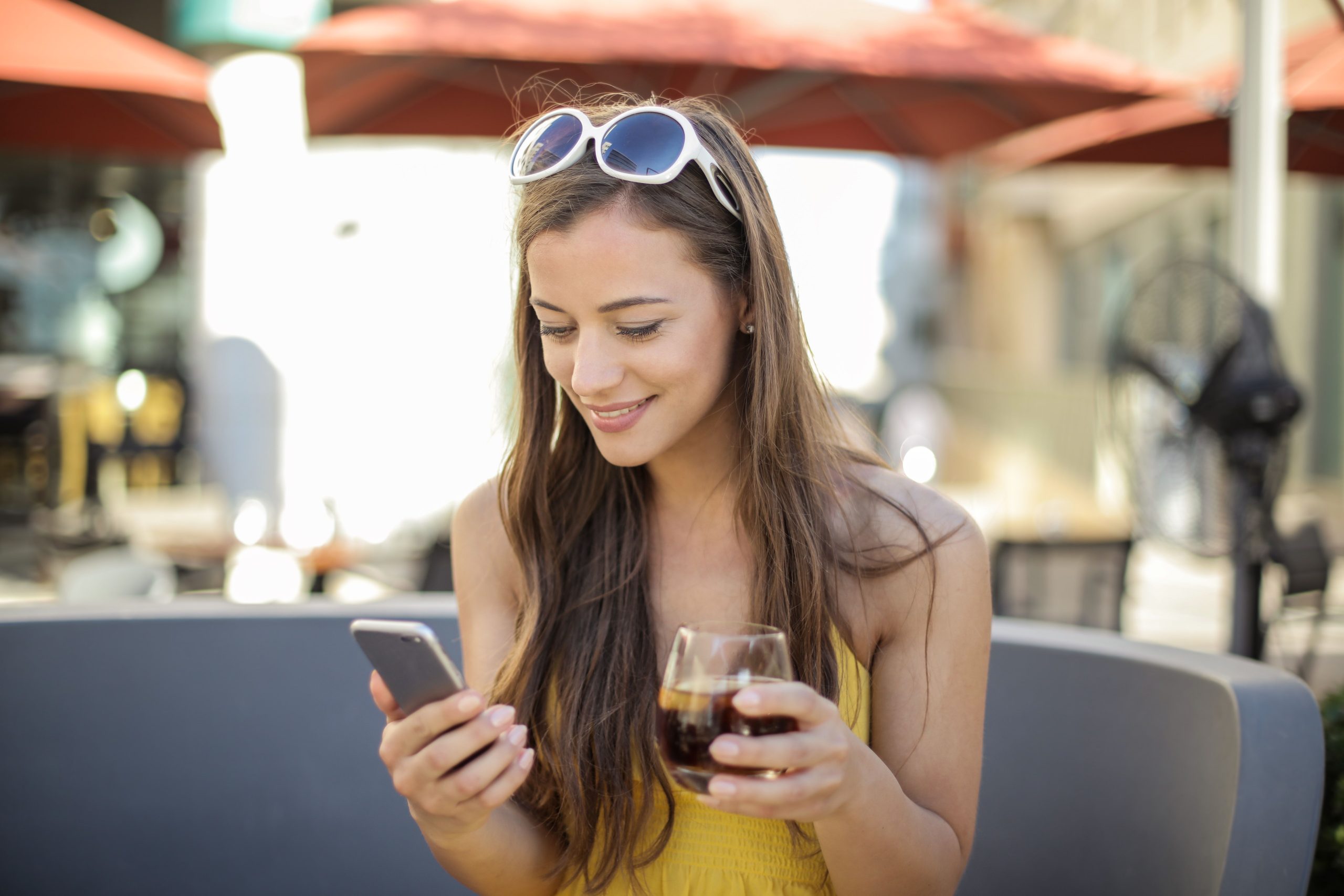 Femme heureuse avec telephone et boisson dehors