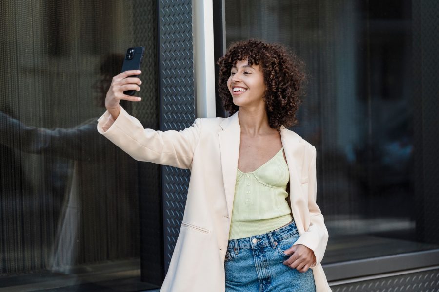 Femme souriante se prenant en selfie devant vitrine