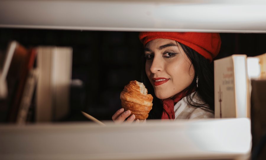 Femme en béret rouge dégustant croissant en bibliothèque
