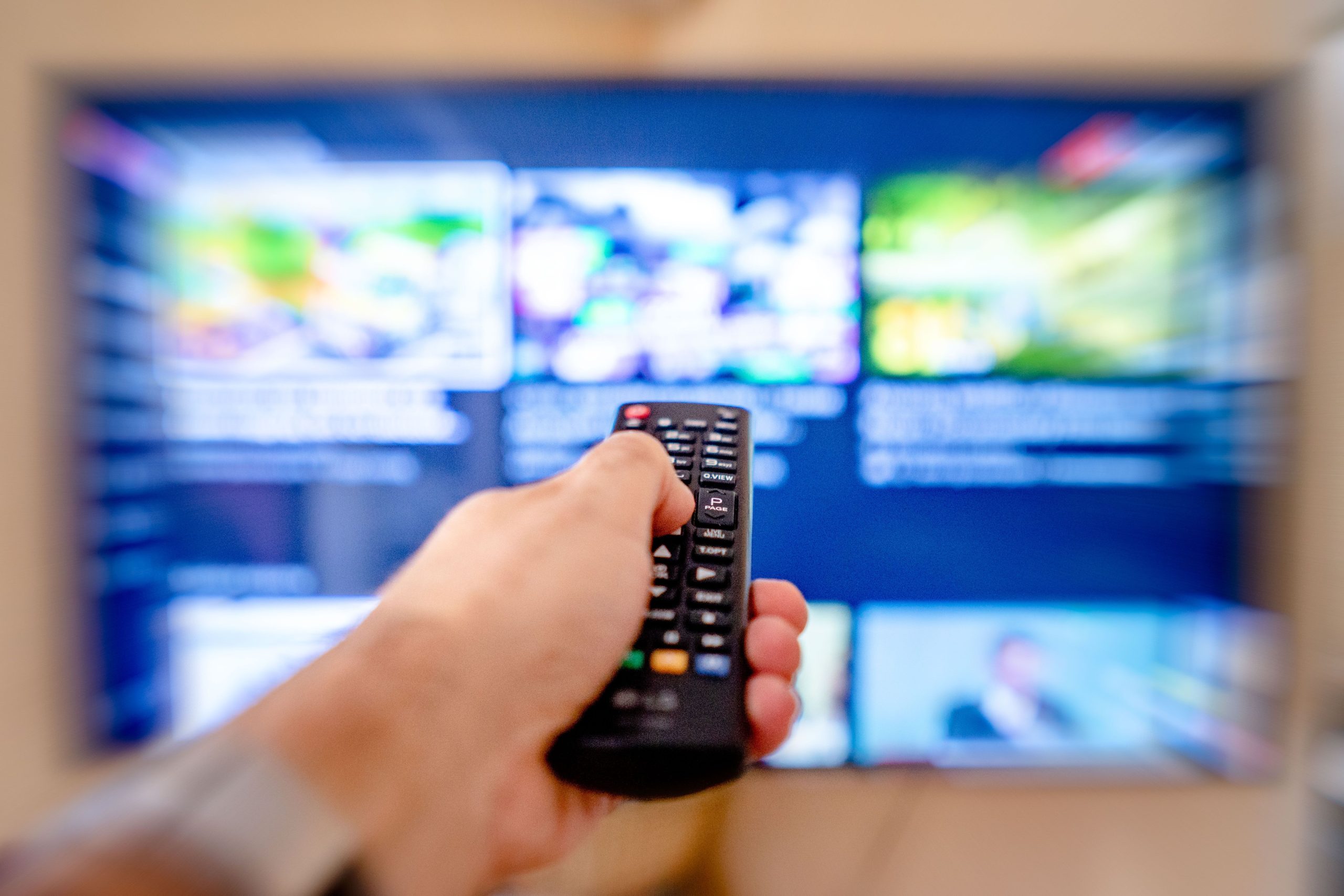 Main tenant une télécommande pointée vers écran TV