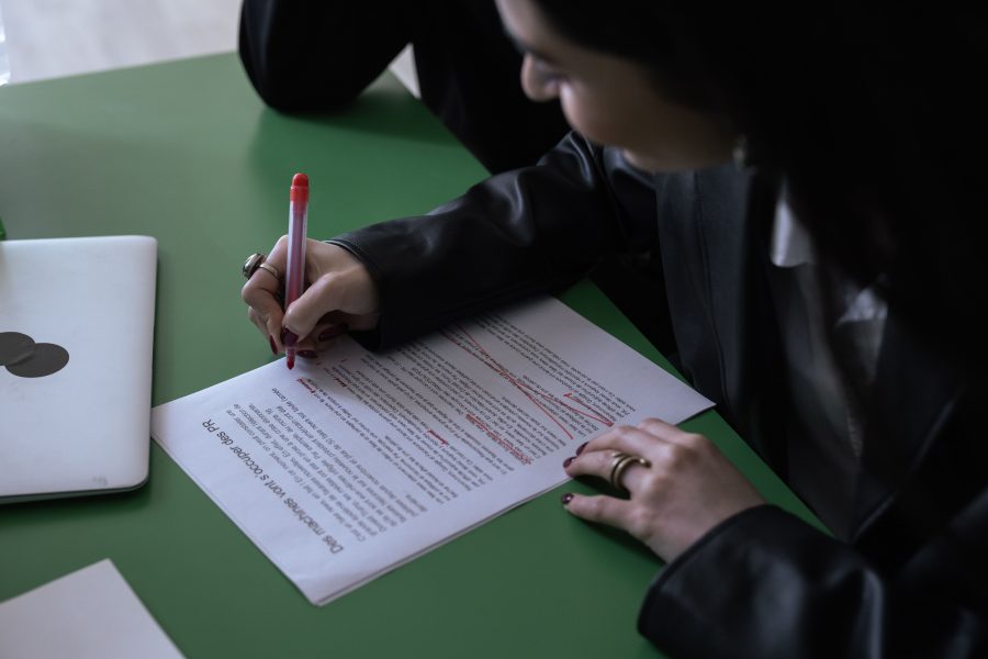 Femme en costume éditant un document avec stylo rouge