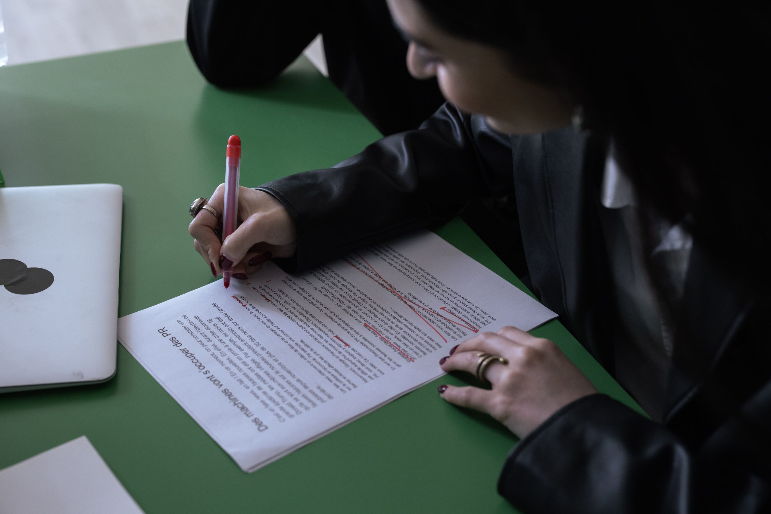 Femme en costume éditant un document avec stylo rouge